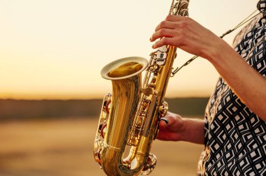 Yetenekli bir müzisyen gün batımında saksafon çalar, yaratıcılığını sakin ve ilham verici bir ortamda ifade eder.