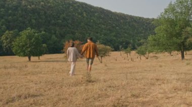 Güneşli bir tarlada el ele yürüyoruz, doğayla iç içe, çarpıcı güzellikler ve sükunetle.