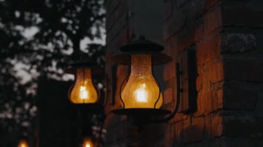 Geleneksel fenerler, akşam karanlığının erken saatlerinde rahat ve davetkar bir dış mekanı hafifçe aydınlatırlar.