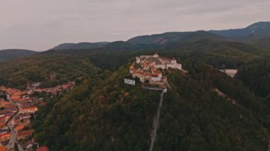 Citadel Rasnov Romaniain 'in çarpıcı hava manzaralı görüntüleri, dağın eteklerinde güzel bir şekilde yerleştirilmiş tarihi bir kaleyi gözler önüne seriyor. .