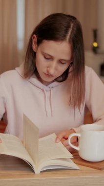 Huzurlu bir an, yanında sıcak bir fincan kahveyle derinden okumaya dalmış genç bir kadını yakaladı.