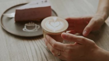 Huzurlu ve huzurlu bir an, ahşap bir masada ağız sulandıran bir dilim kekin yanında lezzetli bir latte sergiliyor.