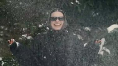 Neşeli bir insan kar yağışının keyfini çıkarıyor, neşeli ve büyüleyici bir kış atmosferine katkıda bulunuyor.