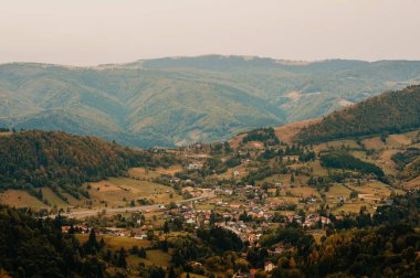 Gelin ve sonbahar boyunca yuvarlanan tepelerin arasına güzel bir şekilde yerleştirilmiş tuhaf bir köyün nefes kesici manzarasının tadını çıkarın.