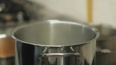 Pürüzsüz, paslanmaz çelik bir tencerenin detaylı bir yakın çekimi, damlacıkları canlı bir şekilde yakalıyor, mutfak dinamiklerini gözler önüne seriyor.