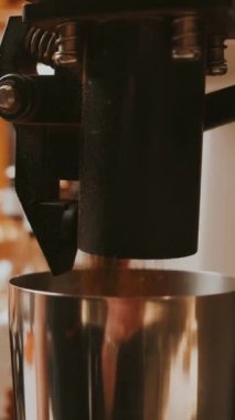Bir kahve makinesinin mahrem görüntüsü ustalıkla servis edilen taze demlenmiş espresso 'yu bekleme kabına koyuyor.
