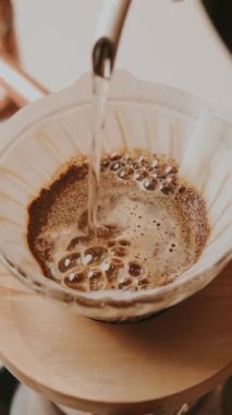 Pourover kahvenin ustalıkla hazırlandığı yakın plan bir görüntü, yükselen aromatik kahve kabarcıklarını vurguluyor
