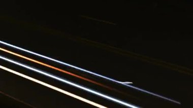 Bir hava manzarası, geçen araçların bıraktığı dinamik ışık yollarını aydınlatan loş bir yol gösteriyor.