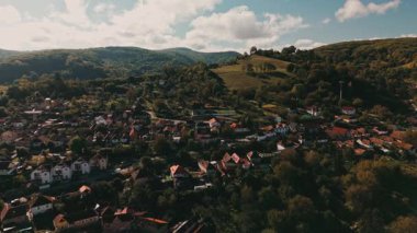 Romanya 'nın Sighisoara Eski Kasabası, sersemletici hava fotoğrafı canlı bir şekilde sergileniyor yemyeşil tepelerde güzel bir şekilde yerleştirilmiş resimli bir köy