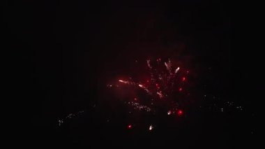 Parlak kırmızı havai fişekler parlak bir şekilde karanlık bir arkaplanda patlayarak canlı ve şenlikli bir atmosfer yarattı.