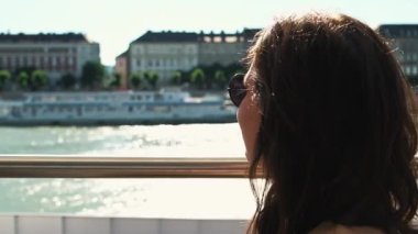 Bir kadın düşünceli bir şekilde güzel nehri seyrediyor, güneşli güzel bir günün tadını çıkarıyor.