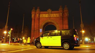 23 Şubat 2023, İspanya, Barselona. İkonik Zafer Takı. Gece sahnesi, renkli şehir ışıkları ve hareketli trafik ışıklarıyla aydınlatılmış tarihi bir kemeri tasvir ediyor.