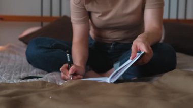 Bir insan yerde oturuyor ve bir deftere yazıyor, yaratıcılığını ifade ediyor ve ilham alıyor.
