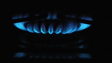 Parlak mavi bir alevin canlı bir yakın çekimi bir gaz ocağında tutuştu ve dans etti, dinamik bir hareketle enerji açığa çıkardı.