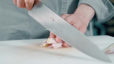 Profesyonel mutfak ortamında taze soğanları ustalıkla doğrayan çok yetenekli bir şef.