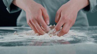 Tezgahta aktif olarak un yoğuran elleri gösteren yakın plan bir görüntü, çeşitli pişirme ve pişirme temaları için mükemmel.