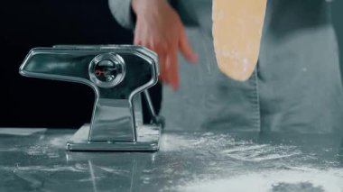 En iyi sonuç için iyi döşenmiş bir yüzeyde klasik bir makarna makinesi kullanarak ustaca el yapımı taze makarna.