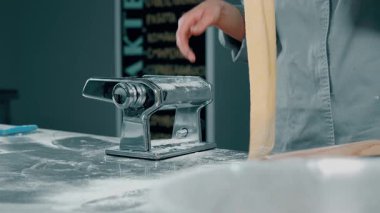 Yetenekli bir şef, geleneksel bir hamur işi kullanarak yeni yapılmış makarna hamurunu ustalıkla sunar.