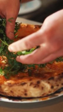 Yetenekli bir şef lezzetli bir pizzaya taze roka ekler, lezzetini ve sunumunu arttırır, onu çekici kılar.