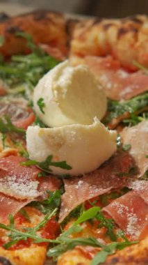 Lezzetli prosciutto, taze roka ve kremalı burrata peynirli lezzetli bir pizzanın tadını çıkarın.
