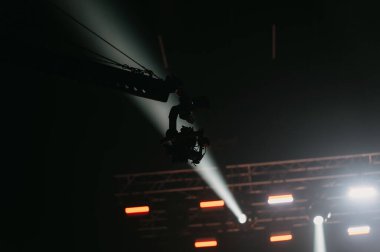 Büyüleyici bir performans sırasında sahne aydınlatma ekipmanlarının yukarıdan çekimleri, dinamik ışık huzmeleri oluşturur.