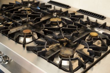 Lekeli bir gaz sobasının detaylı bir görüntüsü, mutfak veya mutfak teması için uygun ağır kullanımı gösteriyor.