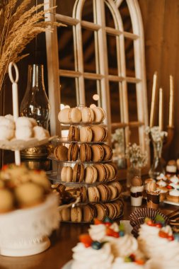 Nefis badem kurabiyeleri, renkli kekler ve zarif kırsal dekorların yer aldığı güzel bir tatlı masası.