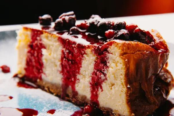 Lezzetli bir dilim cheesecake, güzel süslenmiş zengin böğürtlen sosu ve lezzetli malzemelerle