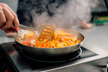 Yetenekli bir şef elektrikli ocakta renkli sebzeleri karıştırarak gerçekten lezzetli bir yemek yapar.