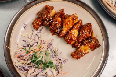 Lezzetli tavuk kanatları yanında çıtır lahana salatası servis edilir, partiler ve sosyal toplantılar için ideal.