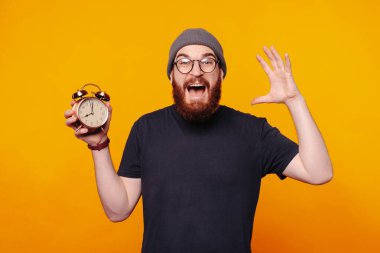 Çok neşeli bir adam elinde bir çalar saati tutarak zamanın harika neşesini kutluyor.