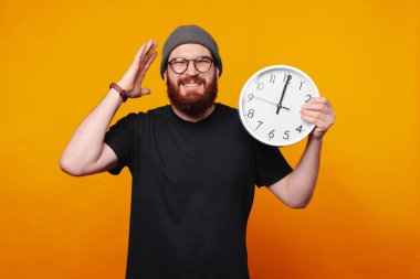 Saati tutan neşeli, güler yüzlü bir adam. Parlak ve hayat dolu bir ortamda aciliyet ya da sürpriz gösteriyor.