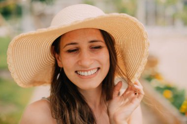 Şık güneş şapkalı neşeli bir kadın sıcak güneş ışığında güneşleniyor, kaygısız, neşeli ve mutlu bir anın tadını çıkarıyor.