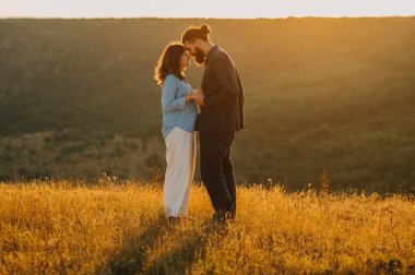 Sıcak ve samimi bir anı paylaşan sevgi dolu bir çift sakin bir açık hava ortamında gün batımında