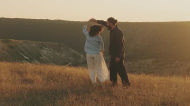 Sevimli bir çift gün batımında büyüleyici bir altın tarlada neşeyle dans eder. Aşklarının derinliğini kutlarlar.