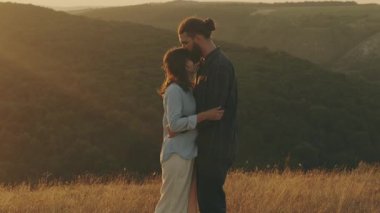 Sevgi dolu bir çift, çarpıcı bir günbatımında doğanın nefes kesici güzelliği arasında derin bir hassasiyet yaşar.