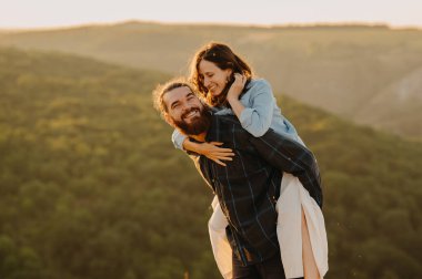 Neşeli bir çift gün batımında büyüleyici doğal manzaranın ortasında neşeli bir anın tadını çıkarıyor.