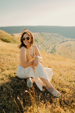 Neşeli ve mutlu bir kadın güneşli bir alanda poz verir, tamamen kucaklayıcı doğası vardır canlı güzellik ve sükunet