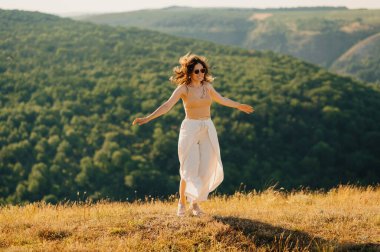 Neşeli bir kadın canlı, gür bir manzarada zarif bir şekilde dans eder, doğası gereği özgürlüğünü kutlar.