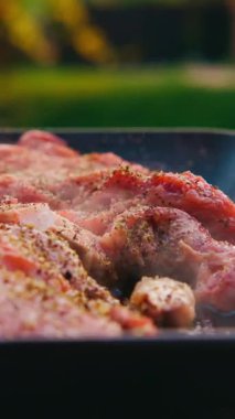 Salamuraya yatırılmış etin cızırdaması ve açık havada ızgarada aromatik otlarla pişirilmesi yakından görülüyor.