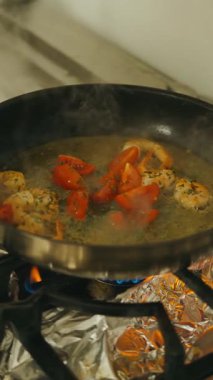 Cızırdayan sıcak tavada taze domatesli lezzetli karides pişirme deneyiminin tadını çıkar.