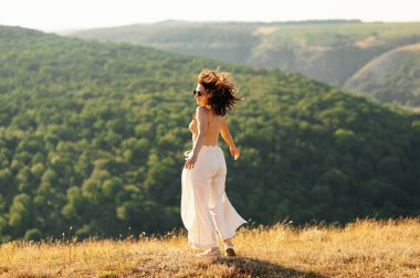 Genç bir kadın açık havada kaygısız ve neşeli bir anın tadını çıkarıyor canlı, yemyeşil manzaraların arasında.