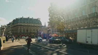 Paris, Fransa. 24 Ekim 2023. Hareketli yayalar, hareketli araçlar ve güneş ışığının oyuncu gölgeler bıraktığı hareketli bir şehir sokak sahnesi.