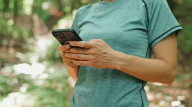 Etrafı sakin ve sakin bir orman ormanıyla çevriliyken bir insan akıllı telefonuyla derinden meşgul olur.