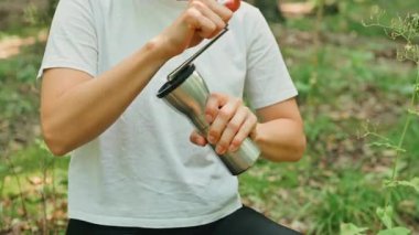 Bir insan doğanın güzelliğinin tadını çıkarırken portatif bir aletle dışarıda lezzetli bir içecek hazırlıyor.