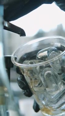 Buzun üzerine serinletici bir içecek serpiştiren bir elin yakından çekimi, içeceğe hazırlanma eylemini yakalıyor.