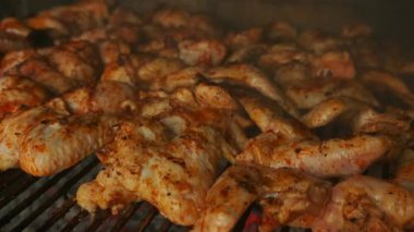 Baharatlı ızgara tavuk kanatları sıcak bir barbeküde lezzetli bir şekilde pişiriliyor. Her türlü eğlence ve parti için ideal.