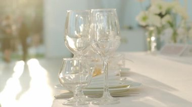 Bardaklar, tabaklar ve canlı çiçeklerle süslenmiş güzel ve zarif bir masa. Etkinlikler için ideal.