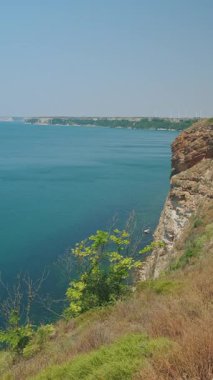 Güneşli bir günde dingin mavi bir denizin üzerinde yükselen nefes kesici sahil kayalıklarına dalın.