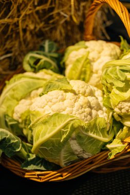 Canlı ve renkli bir karnabahar gösterisi, güzel bir şekilde sade bir sepetin içine yerleştirilmiş.